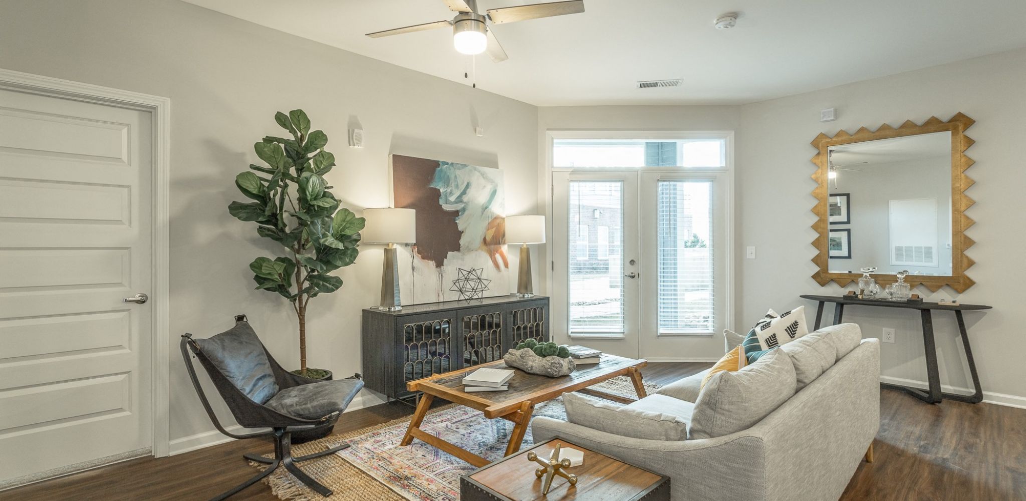Hawthorne at the W apartment living room with large patio doors, furnished with a couch, coffee table, and chair